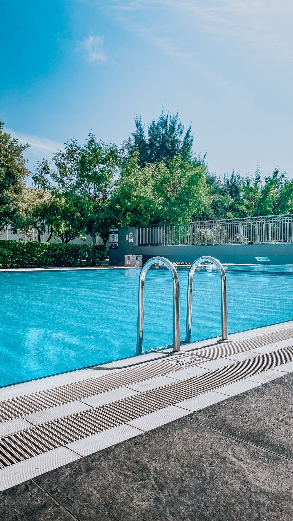 A spotless residential pool with a stainless ladder and clear blue water on a sunny day